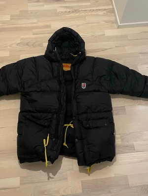 Herr Fjällräven Vinterjacka - Säljer en svart Fjällräven herrjacka. Fick den för ungefär ett år sen men den har tyvärr bara blivit liggande, använd kanske någon enstaka gång max. Är i princip som ny, inga skador, fläckar eller slitage alls. Nypris var 7 499 kr.  Storleken är S, men den är stor i storleken. Jag är 185 cm och den sitter perfekt på mig, så skulle säga att den funkar bra även för M och säkert L beroende på hur man vill att den ska sitta.  Riktigt bra jacka, varm och stilren, säljs bara för att den inte används.