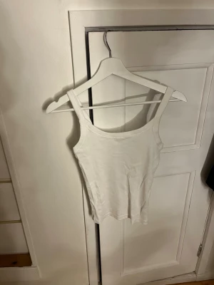 Vit ribbad linnetopp Gina Tricot - Säljer en enkel och stilren vit linnetopp från Gina Tricot, basically basics-kollektionen. Toppen är ribbad med breda axelband och rundad halsringning. Perfekt att styla till jeans eller kjol för en clean look.