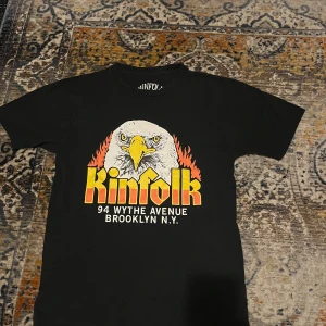 Kinfolk svart t-shirt med örntryck - Svart t-shirt från Kinfolk. Klassisk passform och rund hals. Tillverkad i mjuk bomull som känns skön mot huden. Fint skick, storlek Small