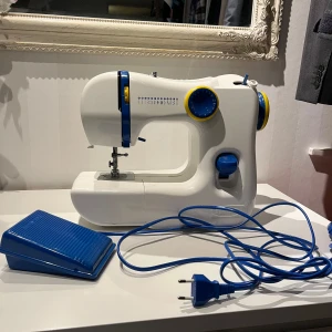 Kompakt elektrisk symaskin – perfekt för nybörjare - Säljer en smidig och lättanvänd symaskin i vitt/blått utförande. Perfekt för dig som vill laga kläder, sy enklare projekt eller är nybörjare inom sömnad. Maskinen tar liten plats och är enkel att plocka fram när kreativiteten slår till.  ✨ Detaljer: 	•	Elektrisk symaskin 	•	Flera sömval 	•	Fotpedal ingår 	•	EU-kontakt 	•	Kompakt och lätt 	•	Fungerar som den ska  📍 Skick: Gott skick 📦 Kan skickas eller mötas upp enligt överenskommelse  Hör av dig vid frågor eller om du vill ha fler bilder!