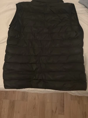 Svart dunväst från C.P. Company M - Säljer en svart dunväst från C.P. Company i modellen PRO-TEK. Västen har quiltad design, hög krage och dragkedjor på fickorna. Tillverkad i stretchig polyester med vattenavvisande yta. Perfekt för lager-på-lager och snygg streetstil.