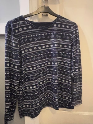 Mörkblå mönstrad pyjamastopp  - Mysig mörkblå långärmad pyjamastopp från mywear woman med vitt vinterinspirerat mönster. Tröjan har rund halsringning och är perfekt för kalla kvällar. Tillverkad i mjukt material för extra komfort.