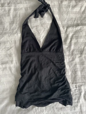 Svart halterneck topp från H&M - Säljer en svart halterneck topp från H&M i storlek M. Toppen har djup v-ringning och knyt i nacken. Materialet är mjukt och stretchigt, perfekt för att styla med jeans eller kjol. Enkel och stilren design utan mönster eller extra detaljer. Skulle säga att den passar xs/s tar gärna emot bud💕😊