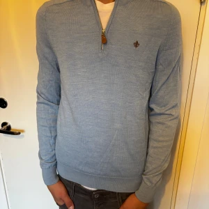 Ljusblå merinoulltröja från Morris - Säljer en stilren ljusblå tröja från Morris i 100% merinoull. Tröjan har half zip med snygg dragkedjedetalj och broderad logga på bröstet. Långärmad och ribbade muddar för en clean look. Använd kanske fem gånger, otroligt bra skick men pris kan såklart diskuteras.
