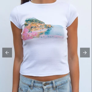 Vit croppad Portofino t-shirt - Säljer en vit croppad t-shirt med färgglatt Portofino-tryck framtill. Toppen har korta ärmar och rund halsringning. Materialet är mjukt och töjbart , men sitter åt till kroppen. Endast använt en gång 