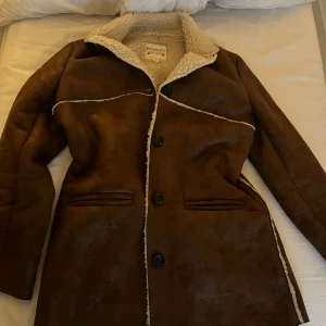 Brun pälsjacka från Mango - Snygg brun pälsjacka från Mango med mysigt foder i offwhite teddy. Jackan har långa ärmar, knappar framtill och markerade sömmar med kontrast. Perfekt för kalla dagar och ger en cool vintagekänsla. Köpte för 1699 kan diskutera priset 🤍