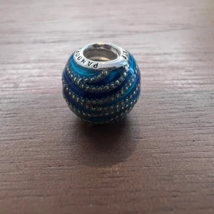 Berlock till Pandora armband - Rund, blå våg berlock i silver till Pandora armband. Så gott som nytt. Använt färre än 10 gånger. (Armband ingår ej i priset)