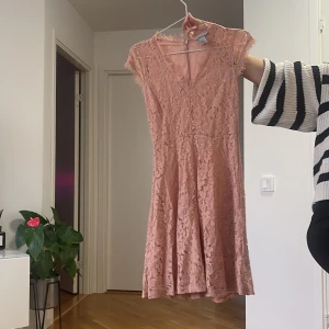 Rosa spetsklänning med v-ringning - Superfin rosa kortklänning från H&M i spets med v-ringad hals och korta ärmar. Klänningen har en romantisk känsla med fina spetsdetaljer och lätt utställd kjol. Perfekt för vår och sommar när du vill känna dig extra söt.