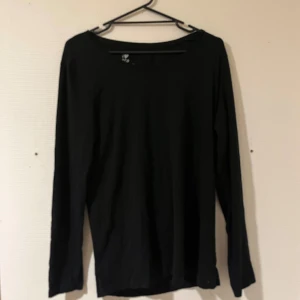 Svart långärmad tröja i bomull - Enkel svart långärmad tröja med rund halsringning. Tillverkad i mjuk bomull, perfekt för lager-på-lager eller som basplagg. Stilren och tidlös design som funkar till det mesta.