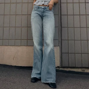 Ljusblå bootcut jeans low waist  - Säljer ett par ljusblå jeans med riktigt snygg bootcut-passform och hög midja. Jeansen har klassisk femficksdesign och är tillverkade i mjukt denimtyg. Perfekta för dig som gillar en retrovibe och vill ha ett par jeans som sticker ut.