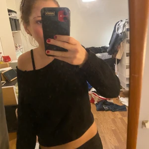 Svart croppad stickad tröja - Svart croppad stickad tröja med bred halsringning som kan bäras offshoulder. Långärmad och mjuk, perfekt för lager-på-lager under höst och vinter. Enkel och stilren design som passar till jeans eller kjol.