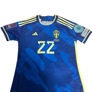 Svensk landslagströja Kafaji #22 Adidas - Blå svensk landslagströja från Adidas med gula detaljer, nummer 22 och Kafaji på ryggen. Det står även Kafajis autograf på ryggen. Tröjan har korta ärmar, tryckta märken och officiella UEFA-patchar på ärmarna. Materialet är lätt och andas, perfekt för match eller träning.