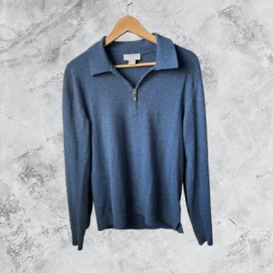 Blå stickad tröja från Tiger of Sweden - Snygg blå stickad tröja från Tiger of Sweden med krage och half zip-dragkedja framtill. Tröjan har långärmad design och är tillverkad i mjukt material som passar perfekt för kyliga dagar. Enkel och stilren look som funkar till många outfits.