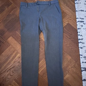 Grå kostymbyxor med raka ben - Snygga grå kostymbyxor från Les Deux i slim fit Byxorna har bälteshällor, knapp och dragkedja fram samt diskreta fickor bak. Perfekta för en clean och stilren look.