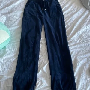 Mörkblå mjukisbyxor Juicy Couture S - Mörkblå mjukisbyxor från Juicy Couture med bred resår i midjan och snörning. Byxorna har stora fickor fram och bak med knappdetaljer. Sköna och loose fit, perfekta för chill dagar. Mjukt material som känns lyxigt mot huden. Varan har täcken på användning endast innanför byxorna längst ned, så inget som syns utanpå❤️