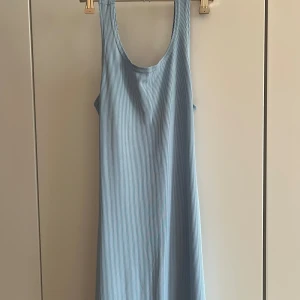 Ljusblå ribbad långklänning med cut out - Säljer en ljusblå ribbad långklänning från Bershka. Klänningen är ärmlös med rund halsringning och har en snygg cut out-detalj i ryggen. Materialet är mjukt och stretchigt, perfekt för sommarens varma dagar.