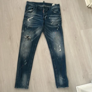 Dsquared2 slim jeans med färgstänk - Snygga blå jeans från Dsquared2 i slim fit-modell med slitningar, hål och färg. Storlek 48 o den passar mig med replay jeans W32 L32