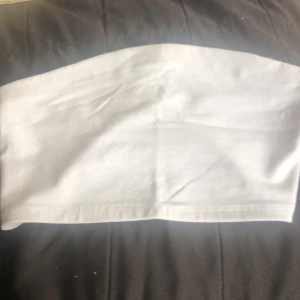 Vit bandeau tubtopp från 157 - Enkel och stilren vit bandeau tubtopp från 157 i storlek XS/S. Toppen är ärmlös och axelbandslös, perfekt för varma dagar eller lager på lager. Tillverkad i mjuk bomull med stretch för en bekväm passform. Snygg att matcha med jeans eller kjol.