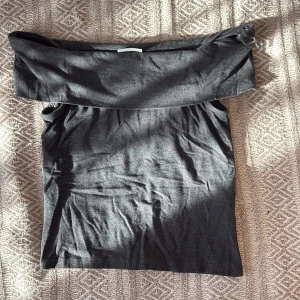 Mörkgrå offshoulder topp Kappahl - Säljer en mörkgrå offshoulder topp från Kappahl i storlek 146/152. Toppen är ärmlös och har en bred kant upptill som ger en snygg och trendig look. Perfekt att styla med jeans eller kjol för en chill vibe.