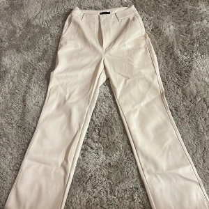 Bootcut skinnbyxor Gina Tricot - Snygga beiga byxor från Gina Tricot i skinnimitation med boocut ben och hög midja. Använda en gång. Storlek 32/XS. Pris kan diskuteras 💕💕