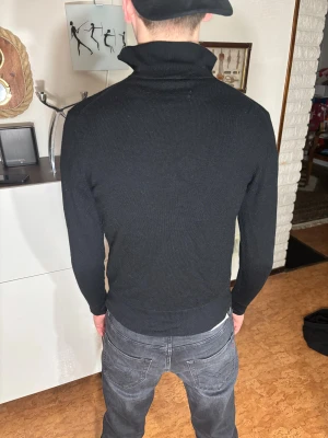 These glory days half zip - Svart polotröja med half zip och lång ärm. Tröjan har en hög krage som kan bäras uppvikt eller nedvikt och är tillverkad i ett mjukt stickat material. Passformen är slim och den är enkel att matcha med jeans eller andra plagg. Modellen är 182 cm och väger 63 kg.