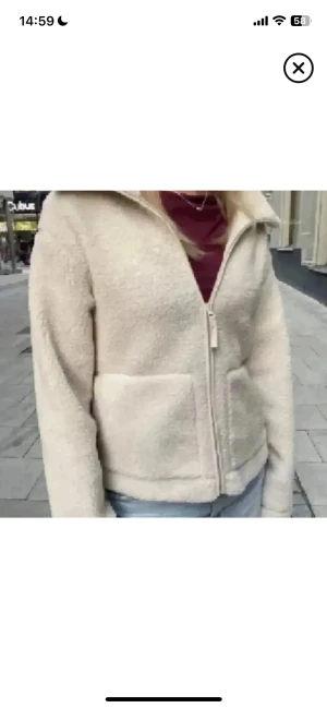 Beige teddyjacka med dragkedja - Mysig teddyjacka i beige med hög krage och två stora fickor framtill. Jackan har en rak passform och stängs med dragkedja. Perfekt för dig som gillar en chill och enkel stil. Materialet är fluffigt och ger en skön känsla under kyliga dagar.