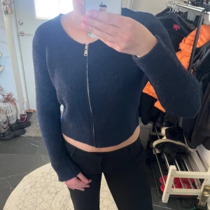 Mörkblå croppad kofta med dragkedja - Säljer en mörkblå croppad kofta från Missay med långärmad design och rund hals. Koftan är stickad och har en snygg dragkedja framtill. Använd få antal gånger.