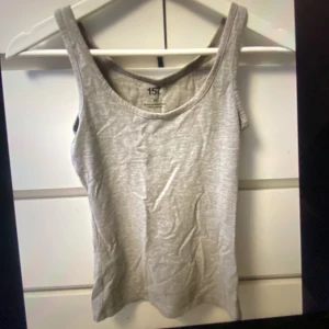 Grå linnetopp från 157, XS - Säljer en enkel och stilren grå linnetopp från 157 i storlek XS. Toppen är ärmlös med breda axelband och har en rundad halsringning. Materialet är mjukt och består av 85% bomull, 10% viskos och 5% elastan. Perfekt för varma dagar eller som layering-piece.