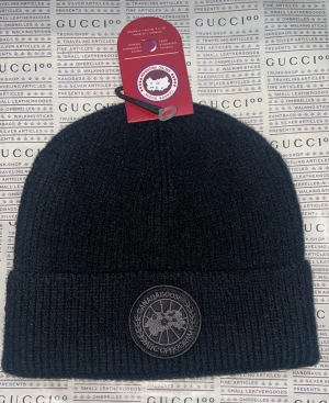 Canada goose black patch  - Ribbstickad mössa från Canada Goose med uppvikt kant och rund svart patch framtill. Finns i olika färger Klassisk form och stilren design, perfekt för kalla dagar. Materialet är mjukt och värmande ull.