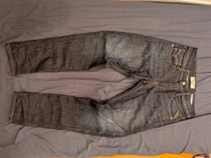 Replay Anbass mörkblå jeans slim fit - Säljer ett par snygga Replay Anbass jeans i mörkblå tvätt med klassiska kontrastsömmar och femficksdesign. Modellen är slim fit och har snygga detaljer som Replay-lapp i skinn baktill och broderade bakfickor. Perfekta jeans för dig som gillar stilren look.