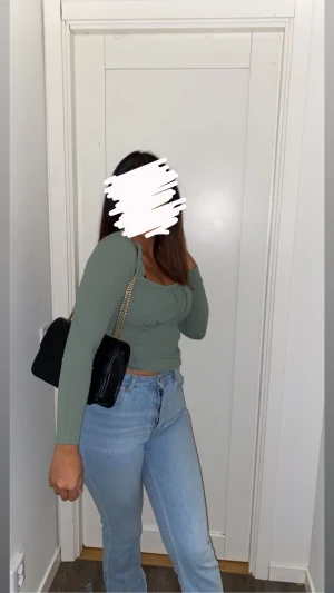 Grön ribbad topp från Bubbleroom - Säljer en snygg ljusgrön långärmad topp från Bubbleroom i storlek S. Toppen har ribbad struktur, puffiga axlar och en söt rynkad detalj vid bysten. Modellen är figurnära och har en fyrkantig ringning som ger en trendig vibe.