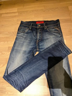 Replay jeans blå W30/L32 - Säljer ett par snygga Replay jeans i blå tvätt och klassiska fem fickor. Modellen har smal passform och normal midja. Jeansen har kontrastsömmar och Replay-logga på bakfickan. Perfekt för dig som gillar stilrena och bekväma jeans. Storlek 30/32, för små för min kille som är 184 och väger 75kg. Modell jondrill. Inga hål eller något annat som påverkar jeansens utseende. Dock tappat lite fäste i en tagg på insidan✨