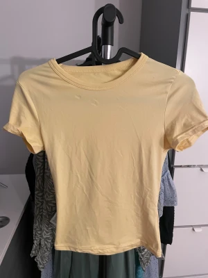 Ljusgul basic t-shirt i bomull - En enkel och fräsch ljusgul t-shirt med rund hals och korta ärmar. Modellen är klassisk och passar perfekt till jeans eller shorts. Materialet är mjukt och skönt bomull som andas bra. Perfekt för dig som gillar stilrena och ljusa plagg.