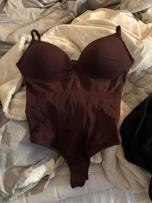 Vinröd korsettbody med axelband - Säljer en vinröd body från H&M med vadderade kupor och smala justerbara axelband. Sitter superfint på och är helt ny o oanvänd då jag köpte fel storlek 