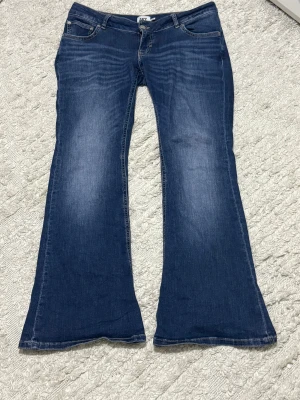 Blå bootcut jeans från 157, stl L short - Snygga blå jeans från 157 i modellen Blaze, storlek L med kort benlängd. Jeansen har klassisk femficksdesign, tydliga slitningar och ett bootcut-snitt som ger en schysst retro vibe. Perfekta för dig som gillar lite vidare ben och cool denimstil.