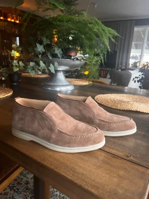 Bruna Loro Piana mockaloafers med vit sula  - Snygga loafers i brun mocka med stilren design och vit platt sula. Skorna har en klassisk rund tå och diskreta sömmar längs ovandelen. Perfekta för dig som gillar en clean och avslappnad look med premiumkänsla. Skriv vid frågor eller funderingar!