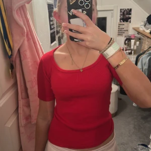 Röd ribbad topp från Hennes Collection - Säljer en röd ribbad topp från Hennes Collection by H&M. Toppen har rundad halsringning och korta ärmar, sitter figurnära och är superenkel att styla till olika looks. den är ribbad oxå. Perfekt för dig som gillar färg och vill ha en klassisk men ändå trendig topp.