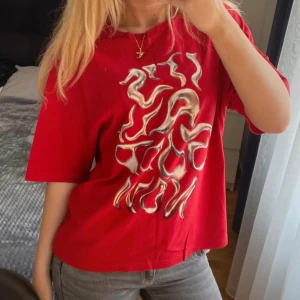 Röd oversized t-shirt med tryck från Bershka  - Röd t-shirt med coolt tryck fram och bak, texten 'IT'S ALL GOOD NOW' på framsidan och futuristiskt motiv på ryggen. Oversized passform, korta ärmar och rund hals. Patch med logga på ärmen. Perfekt statement-plagg för dig som gillar unika prints. Tycker det ger ”The weeknd” vibes!!