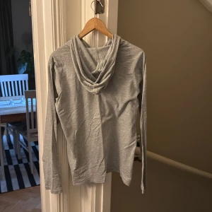 Grå hoodie från Ralph Lauren - Säljer en stilren grå hoodie från Ralph Lauren med klassisk huva och snörning. Tröjan har lång ärm och är tillverkad i mjuk bomull. Diskret logga på. Perfekt för en chill och avslappnad look.