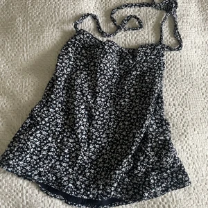 Blommig omlottkjol från BikBok – stl S - Supersöt omlottkjol i mörkblå  med vitt blommönster 🌸 Figursmickrande modell med knytband i midjan och mjukt innertyg för extra komfort. Passar perfekt till sommar, semester och vardag – både med sneakers och sandaler.  I mycket fint skick, använd ett fåtal gånger.