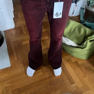 Vinröda bootcut jeansbyxor - Snygga vinröda jeansbyxor med bootcut-snitt och klassisk femficksdesign. Byxorna har en mörk tvätt och är tillverkade i mjukt jeanstyg som ger en skön känsla. Passar dig som vill sticka ut med färg och stil.