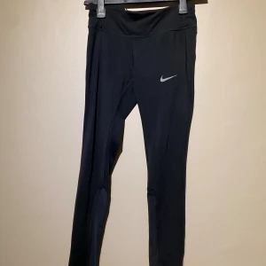 Träningsbyxor Nike Dri fit - Säljer dessa träningstights från Nike Dri fit, dragkedja sitter på rumpan. Polyster och elastan är materialet. Storlek: XS. Finns att hämta i centrala Göteborg eller kan skickas via valfri app. Kan behöva tvätt pga legat i flyttkartonger. 