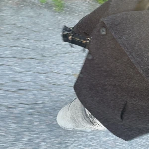 Mörkbrun rock med knappar - Snygg mörkbrun rock med klassisk krage och stora knappar framtill. Jackan har en rak och stilren siluett som passar perfekt till jeans eller dressade byxor. Fickor på sidorna och ett tidlöst uttryck gör den enkel att matcha.