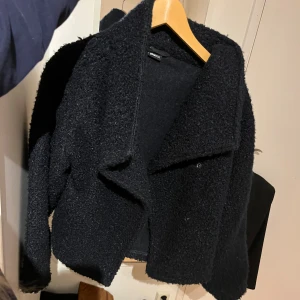 Mörkblå teddyjacka från Gina Tricot XS - Mysig mörkblå teddyjacka från Gina Tricot i storlek XS. Jackan har en oversized känsla, bred krage och är tillverkad i ett fluffigt teddy-material som ger en cool och trendig look. Perfekt för att hålla värmen under kyliga dagar.