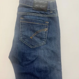 Dondup Monroe jeans blå - Blå jeans från Dondup, modell Monroe Skinny Fit. Snygga kontrastsömmar och klassisk femficksdesign med gul dekorstickning på bakfickorna. Jeansen har smal passform och är tillverkade i jeansmaterial med lätt tvättad look. Jeansen är W31
