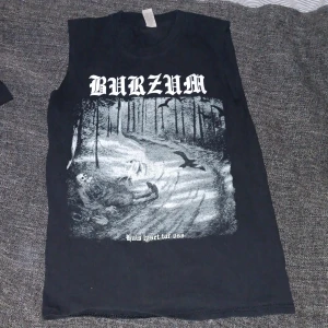 Burzum ärmlös svart band-tshirt - Svart ärmlös t-shirt med tryck från Burzum och albumet 'Hvis lyset tar oss'. Stort grafiskt tryck fram och bak i vitt med skogsmotiv och text. Klassisk rak passform och rund hals. Perfekt för dig som gillar metal och vill sticka ut.