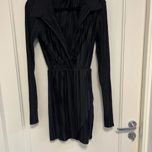 Klänning Missguided S - Säljer en svart omlottklänning från Missguided i storlek 36. Kort modell med snygg omlottfront och lätt v-ringning. Perfekt för dig som gillar stilrena och trendiga plagg. Aldrig använd 