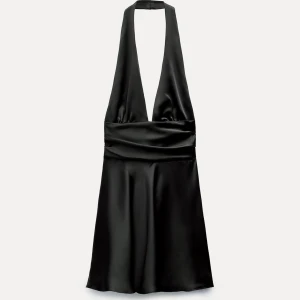 Svart satin halterneck klänning - Supersnygg svart klänning i satin med halterneck och djup v-ringning. Kort modell som ger en cool och elegant vibe, perfekt för dig som vill sticka ut. Materialet är glansigt och mjukt, vilket gör att klänningen faller snyggt och känns lyxig.