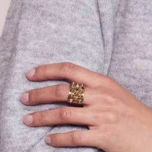 Guldfärgad ring med nitar - Cool och chunky guldfärgad ring med flera spetsiga nitar på ovansidan. Ringen har en bred design och glänsande finish som verkligen sticker ut. Perfekt accessoar för dig som vill ha en edgy och unik stil.