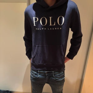 Mörkblå hoodie från Polo Ralph Lauren stl M - Säljer en mörkblå hoodie från Polo Ralph Lauren stl M passar runt 180! Inga defekter men saknar snören vid luvan bortsett från den ordentligta modellen och har inte lyckats få in snörena igen! Vid funderingar är det bara att fråga.